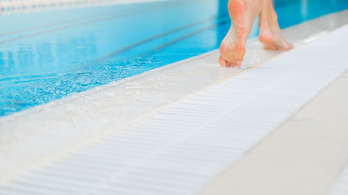 Pieds nus au bord d'un bassin, situation où les chaussettes aquatiques enfant sont utiles